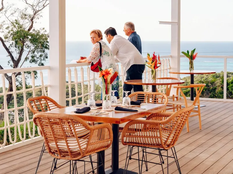 The West Terrace: a table set with flowers on the deck, guests at the rail looking out to sea
